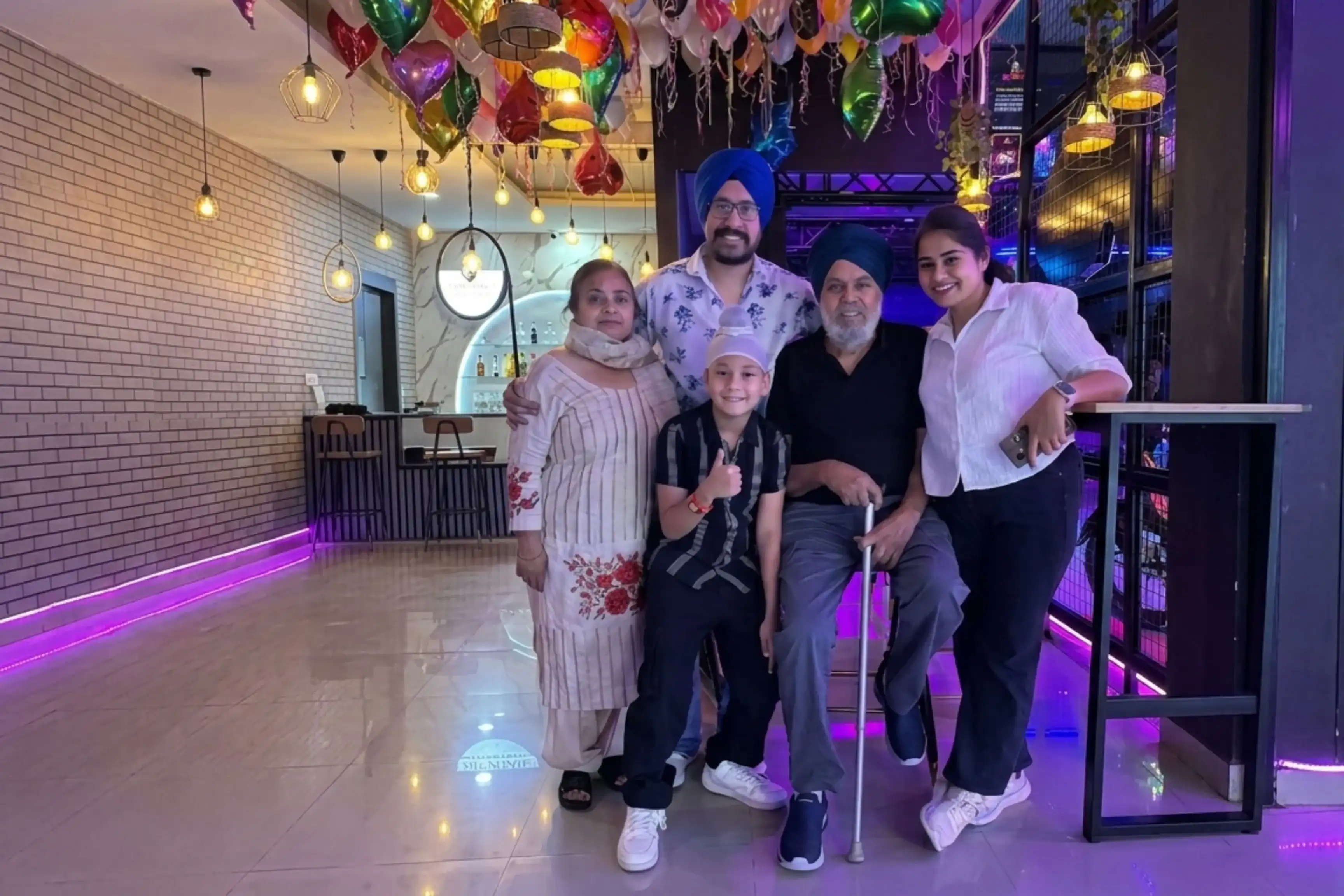 Multi-generational family posing together at Game Xtreme with colourful metallic balloons overhead