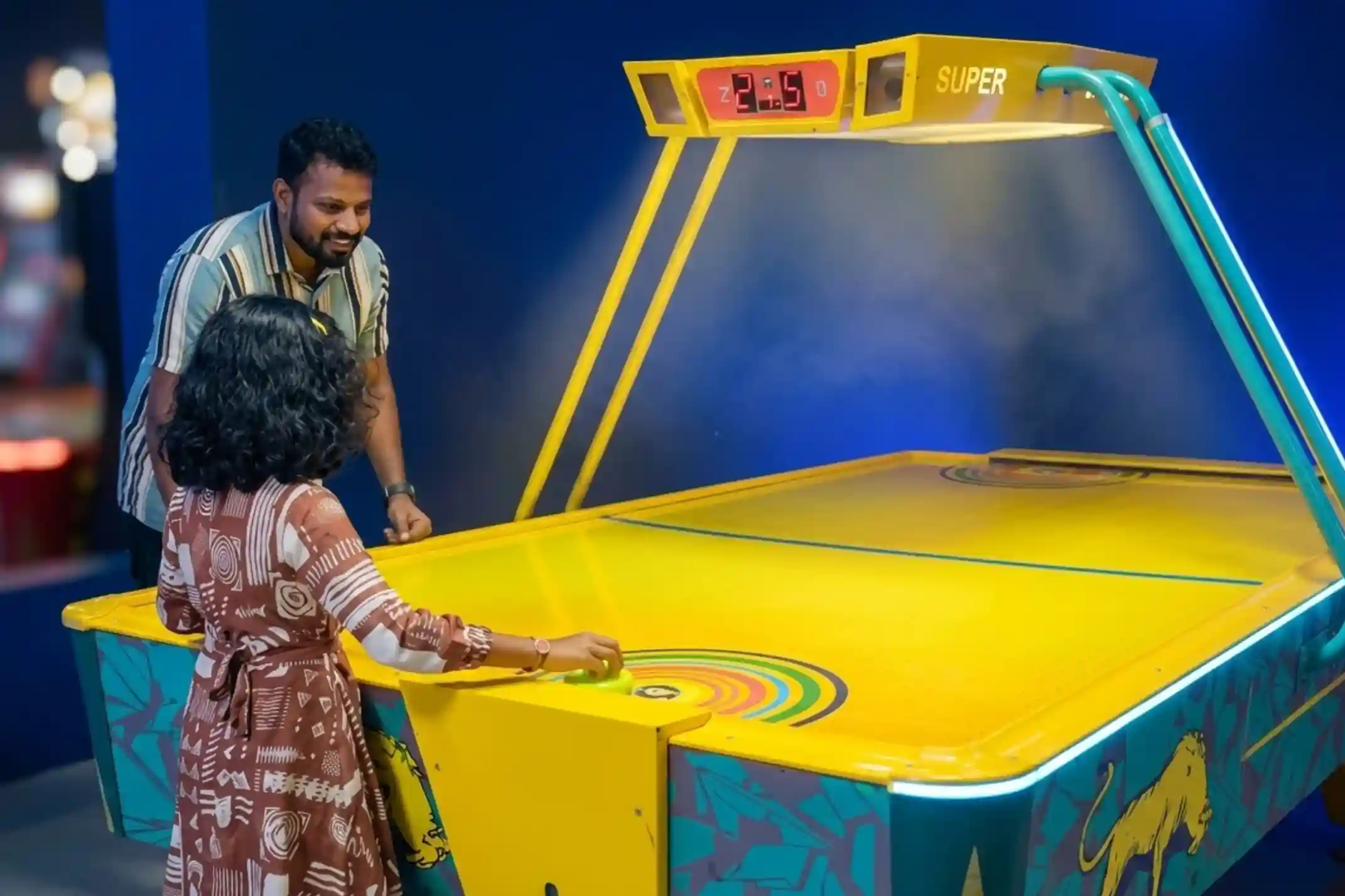 Father and young daughter playing air hockey together at Game Xtreme