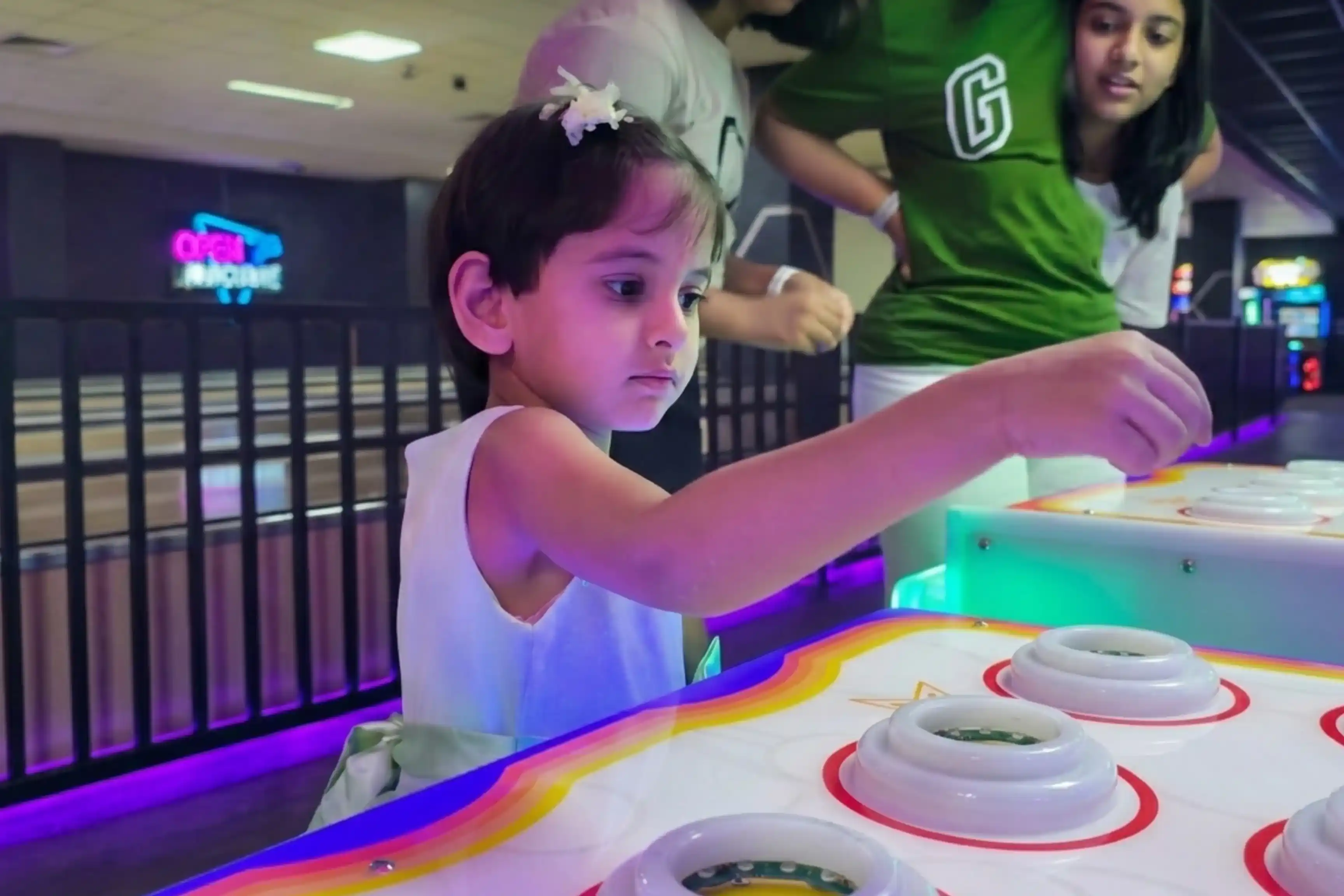 Small girl playing whack-a-mole arcade game with neon lighting
