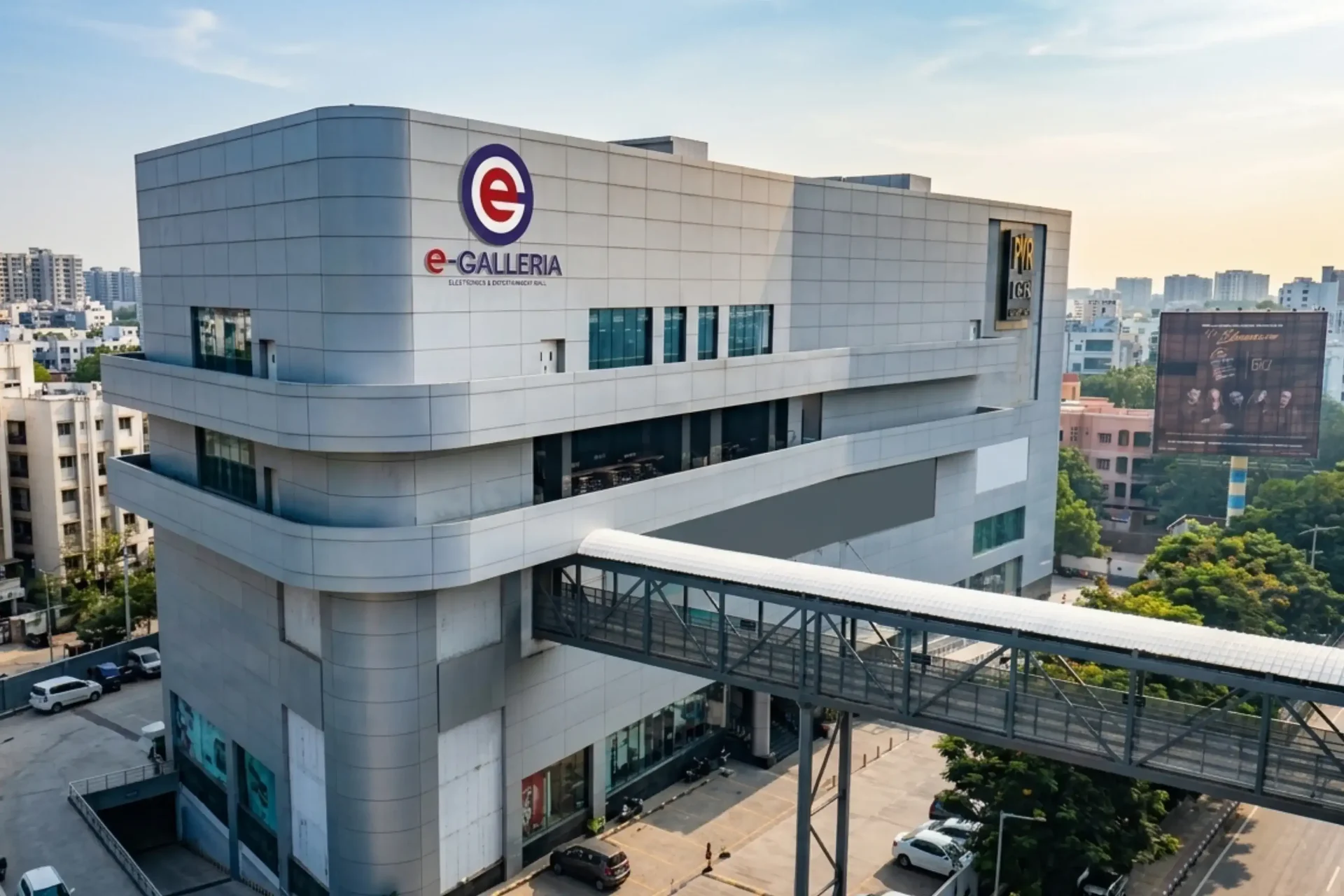 Aerial view of E Galleria Mall building showing the full structure, walkway bridge, and surrounding Madhapur cityscape